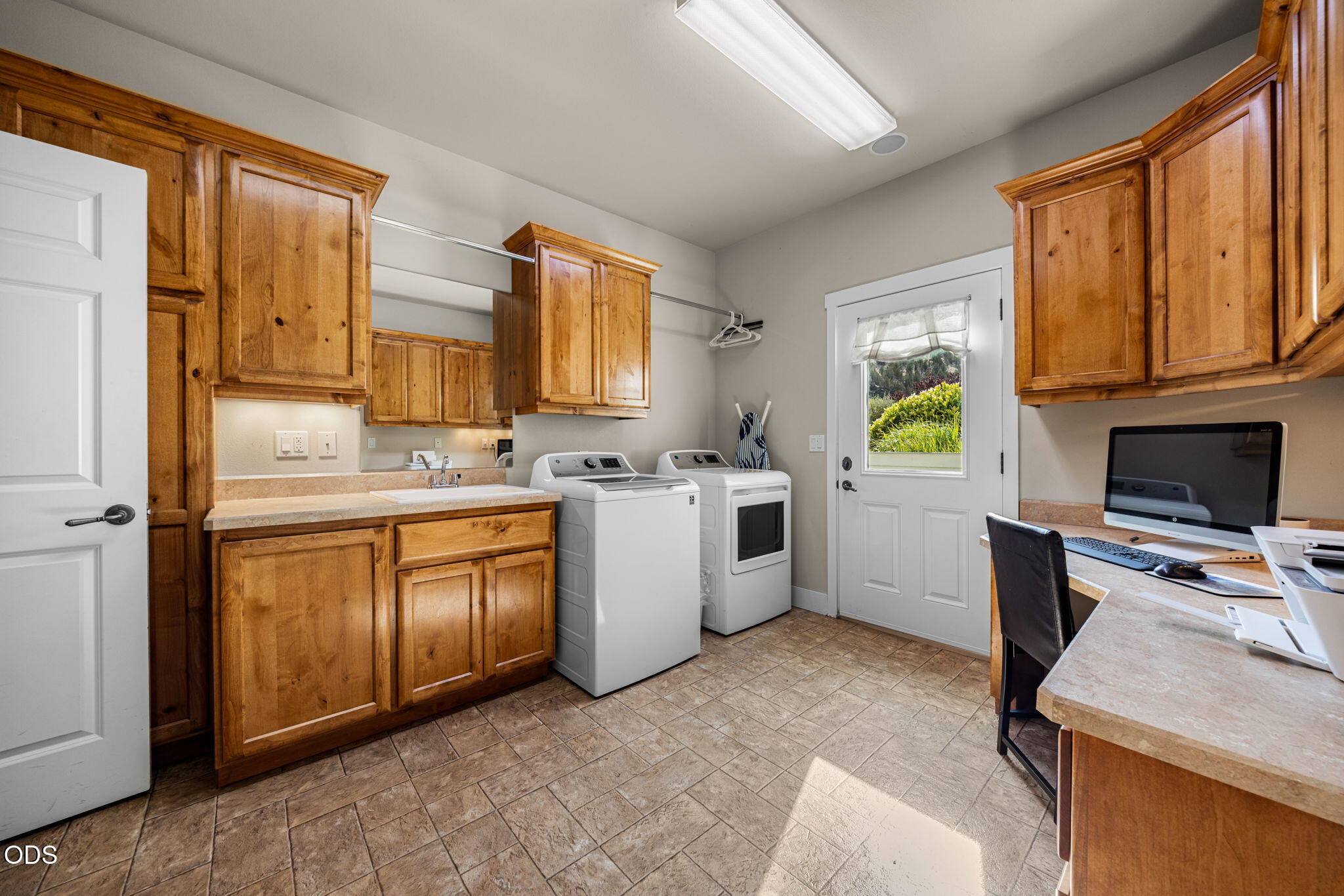 Laundry room with wood cabinets, washer and dryer, utility sink, and built-in desk.