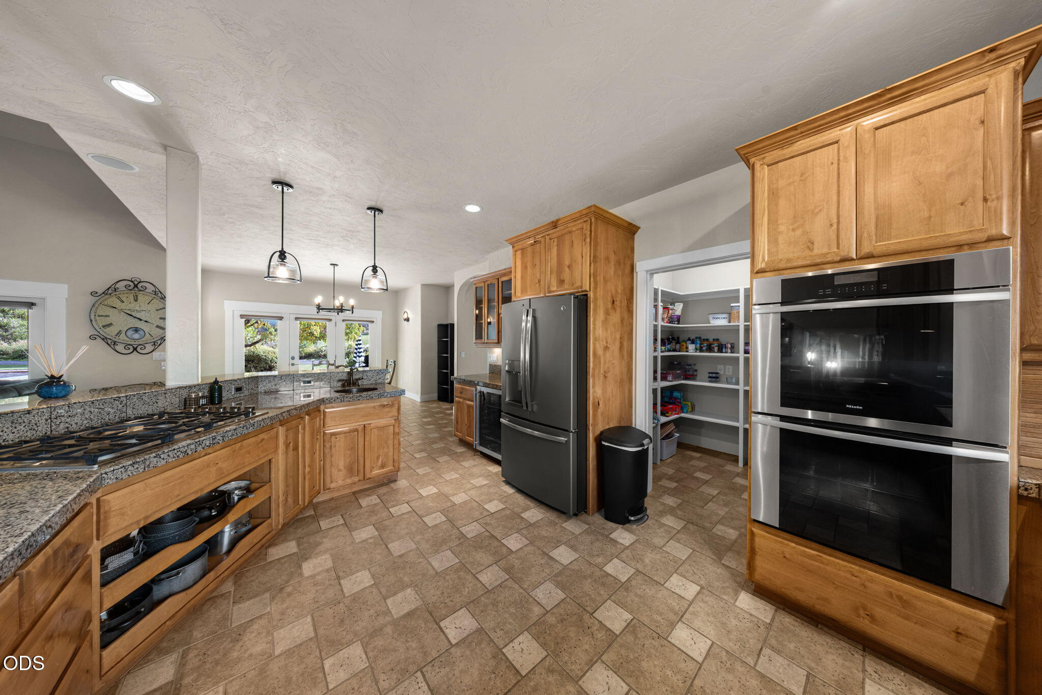 Kitchen with wood cabinetry, granite counters, a gas cooktop, and an open walk-in pantry.