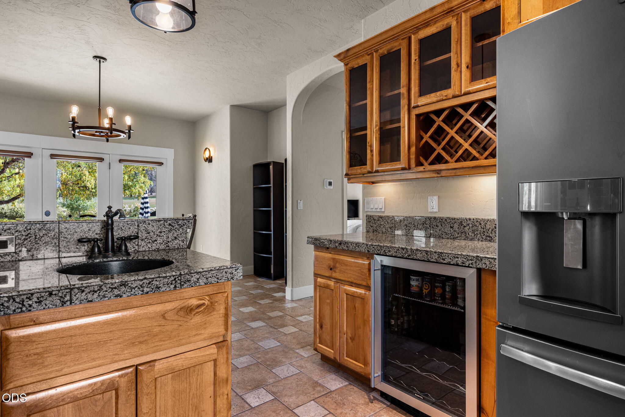 Kitchen with warm wood cabinets, granite counters, a black sink, and a built-in wine rack.