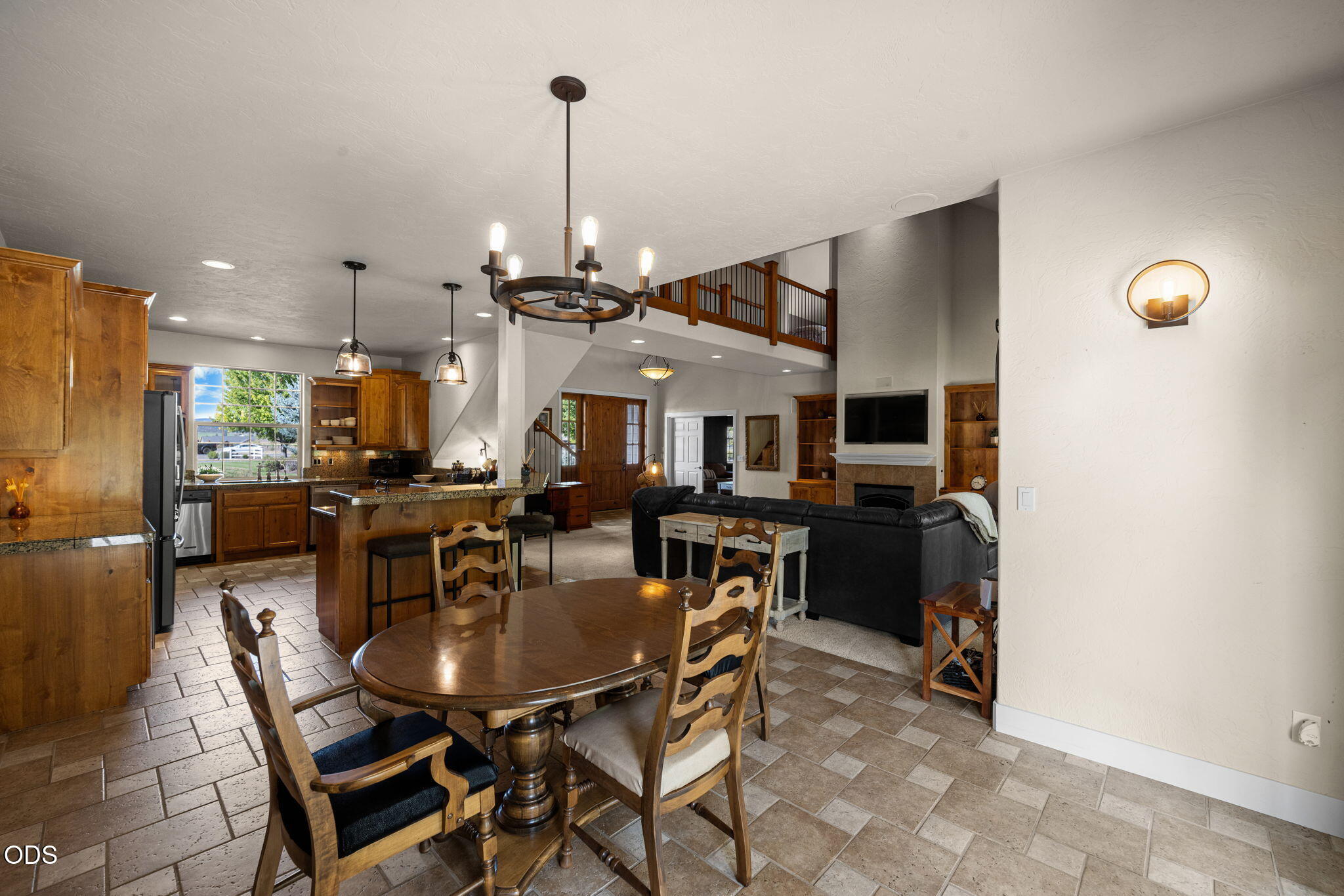 Open-plan kitchen and living room with a granite island, wood cabinetry, and dining table.