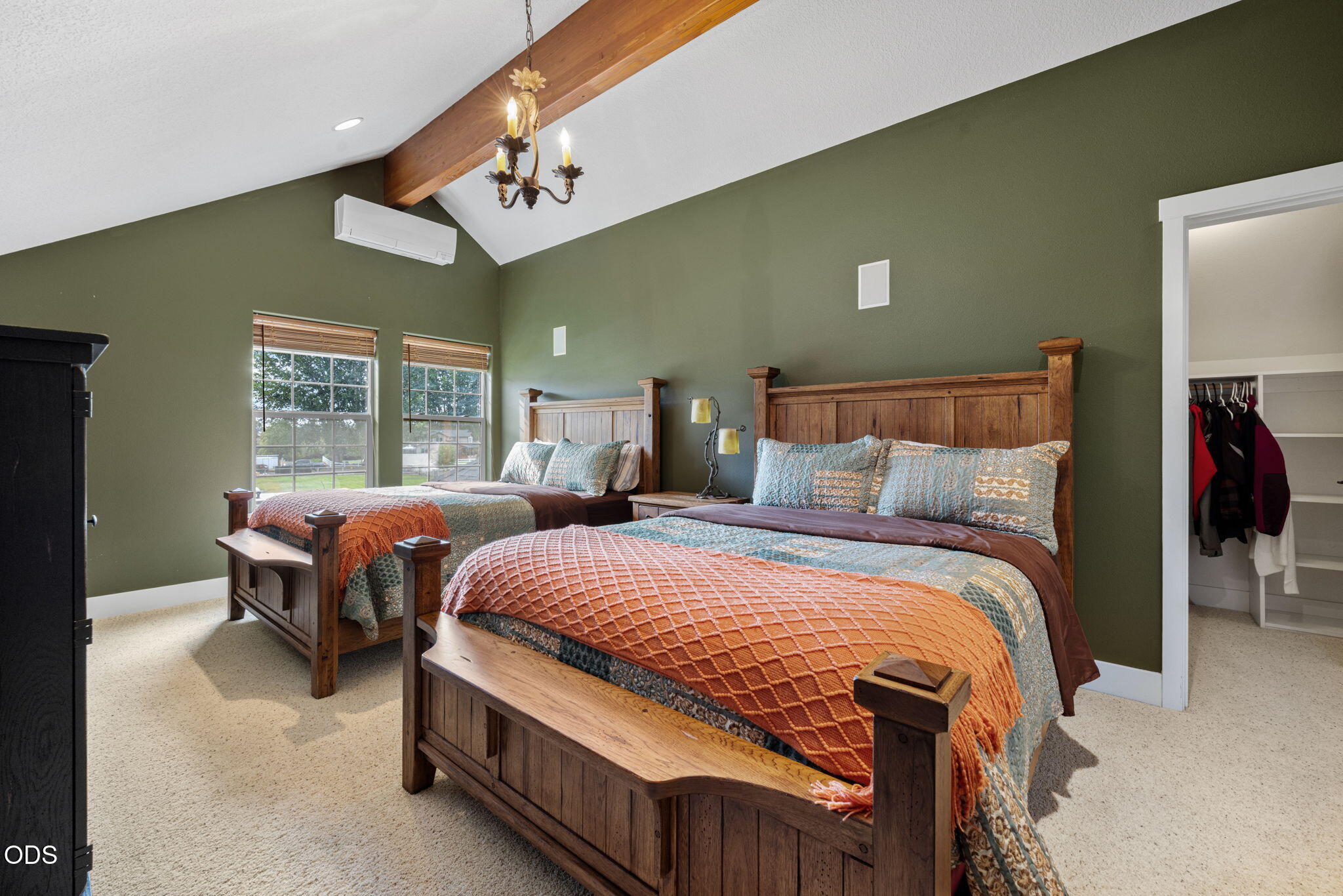 Bedroom with two wooden beds, olive-green walls, and an exposed ceiling beam.