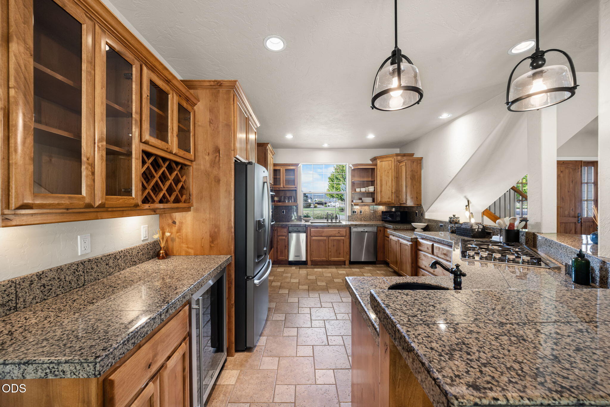 Kitchen with warm wood cabinetry, granite counters, stainless steel appliances, and a large island.