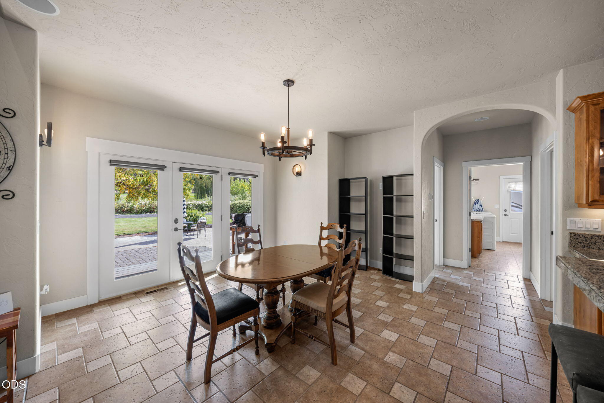 Dining room with a wooden table, tiled floors, and French doors opening to a patio.