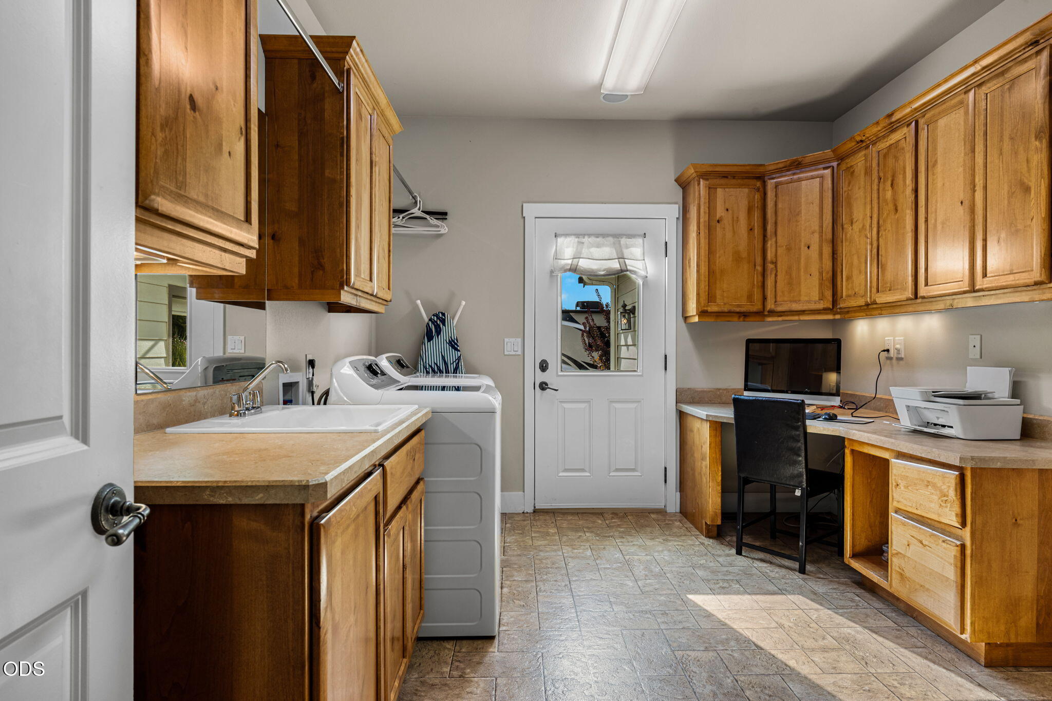 Laundry room with wood cabinetry, washer and dryer, utility sink, and built-in computer desk.