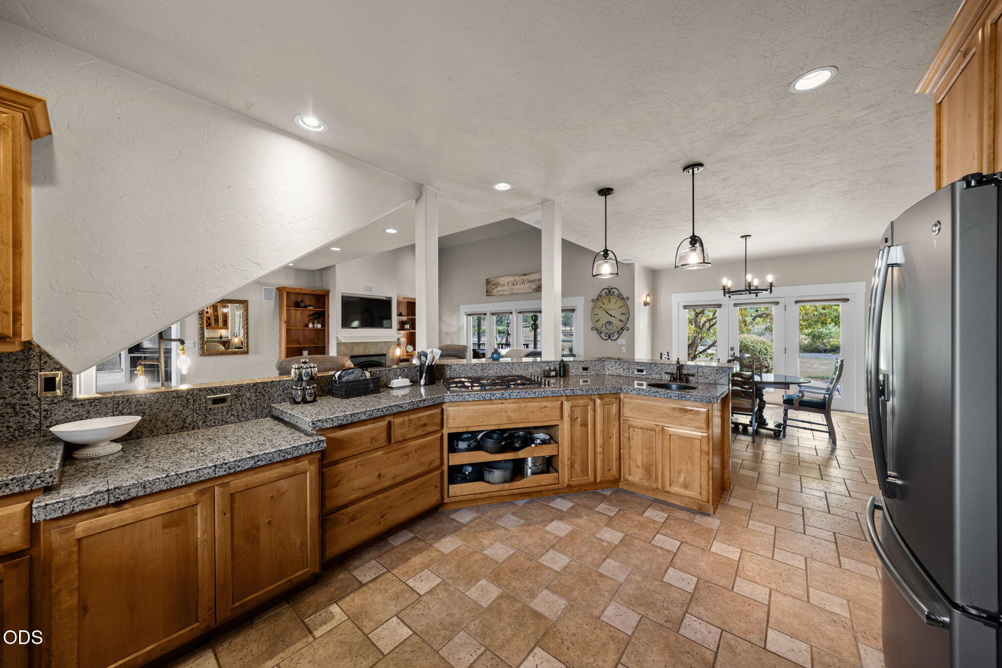 Kitchen with granite counters, warm wood cabinetry, tile floors, and an adjoining dining area.