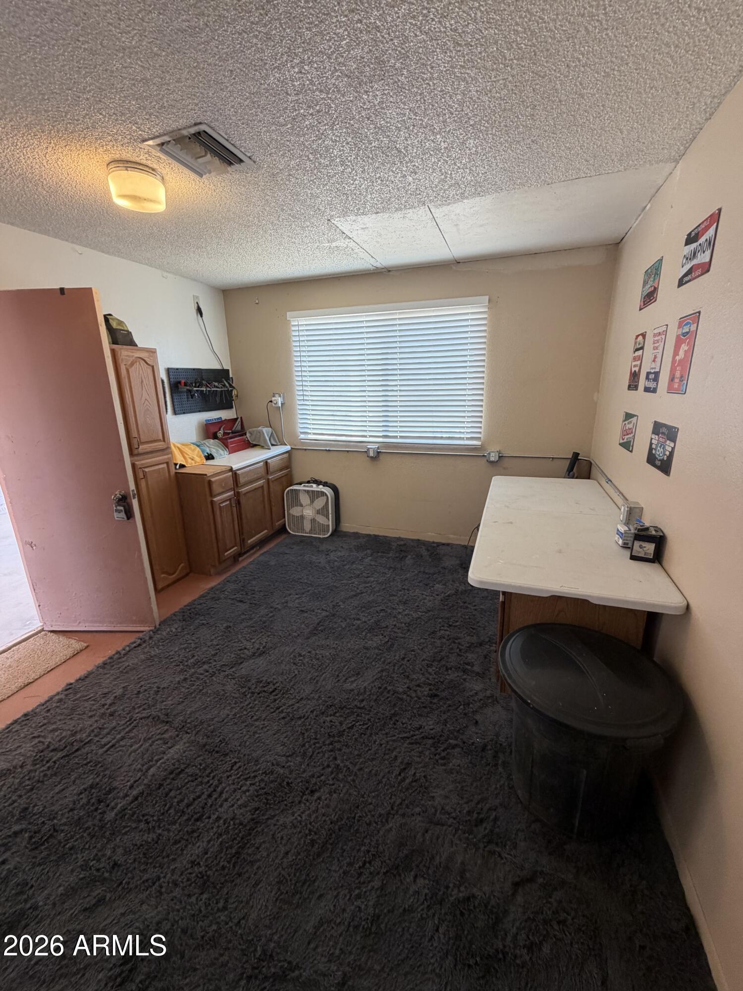 Workroom with wooden cabinets, a tool board, and a table beside a window.