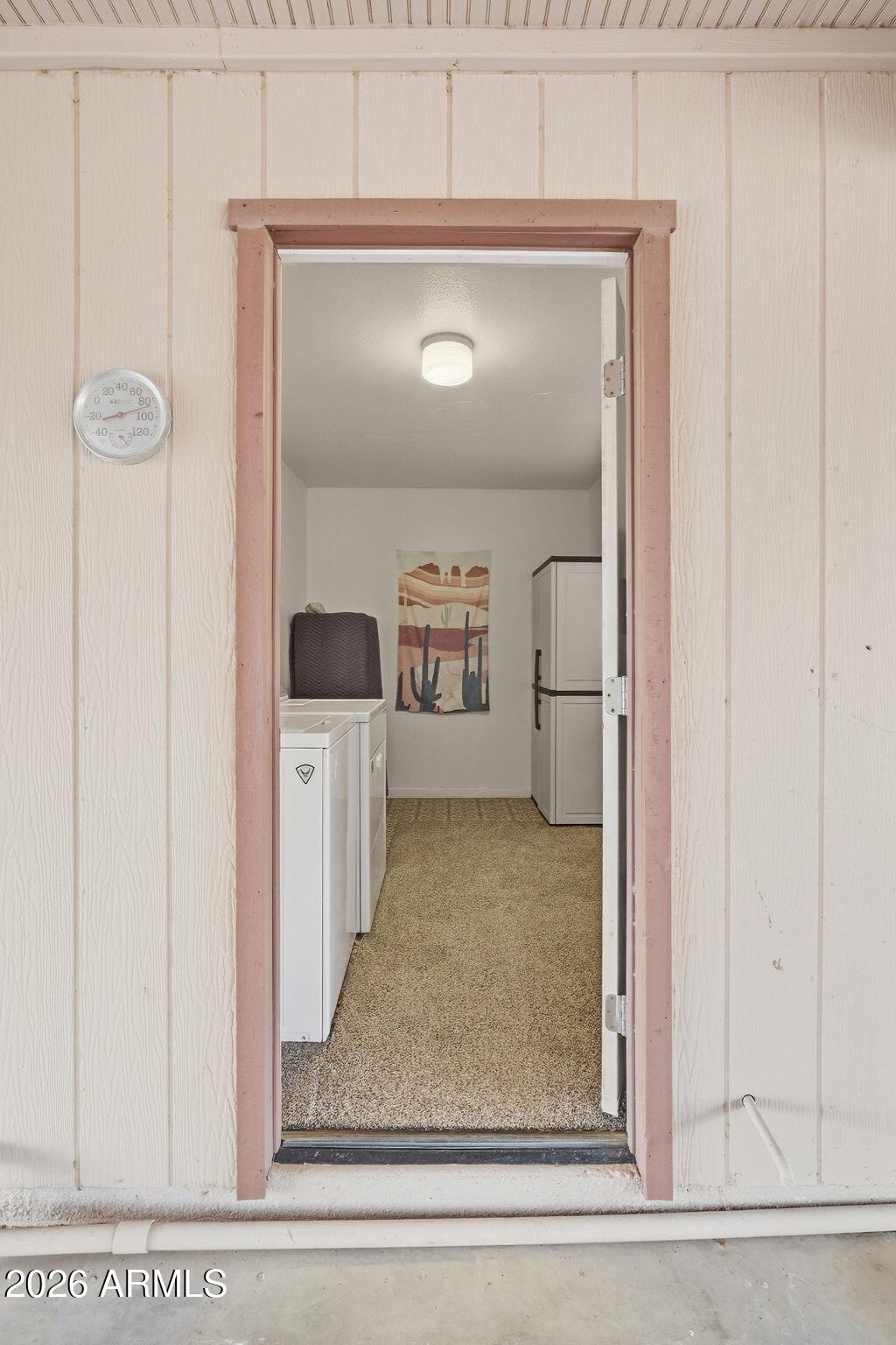 Laundry room with white appliances, a tall freezer, carpeted floor, and Southwestern wall art.