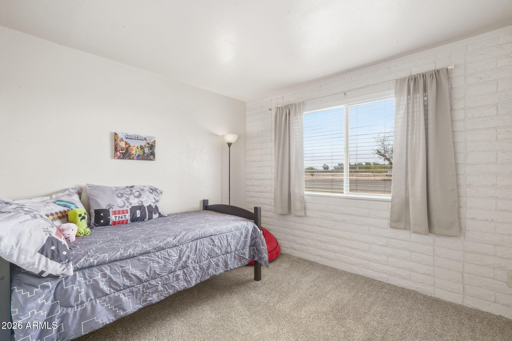 Furnished bedroom with a Minecraft-themed bed, plush toys, and a curtained window.