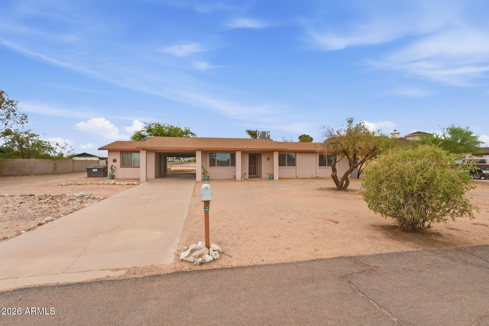 Single-story home with a covered carport, concrete driveway, mailbox, and desert landscaping.