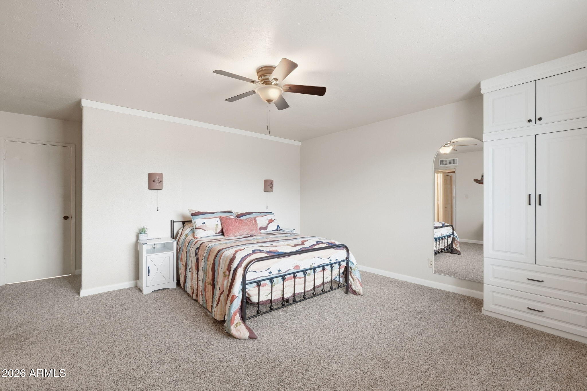 Furnished bedroom with Southwestern-style bedding, a ceiling fan, and a large mirrored built-in wardrobe.