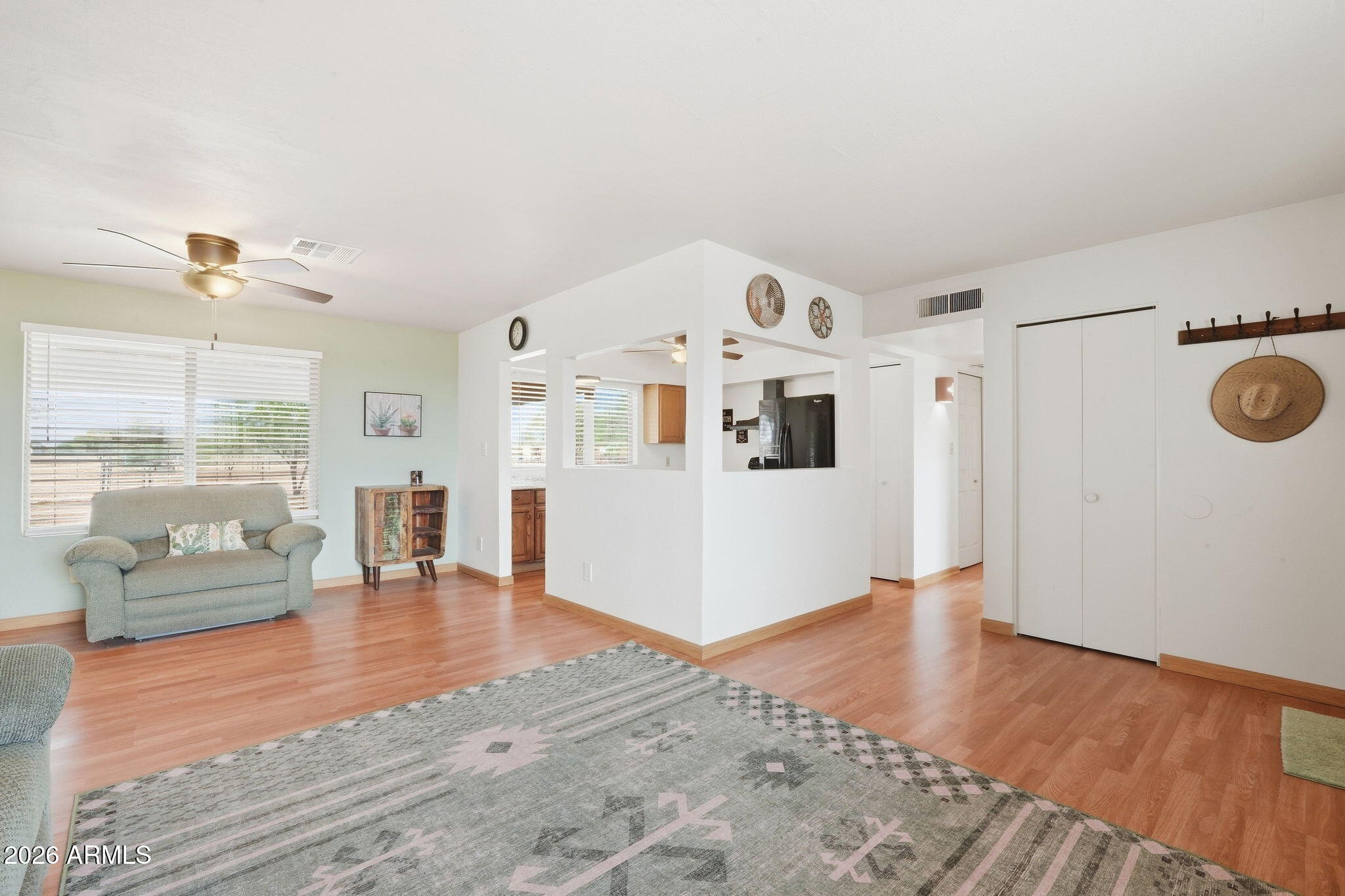 Living room with a patterned rug, ceiling fan, and open pass-throughs to the kitchen.