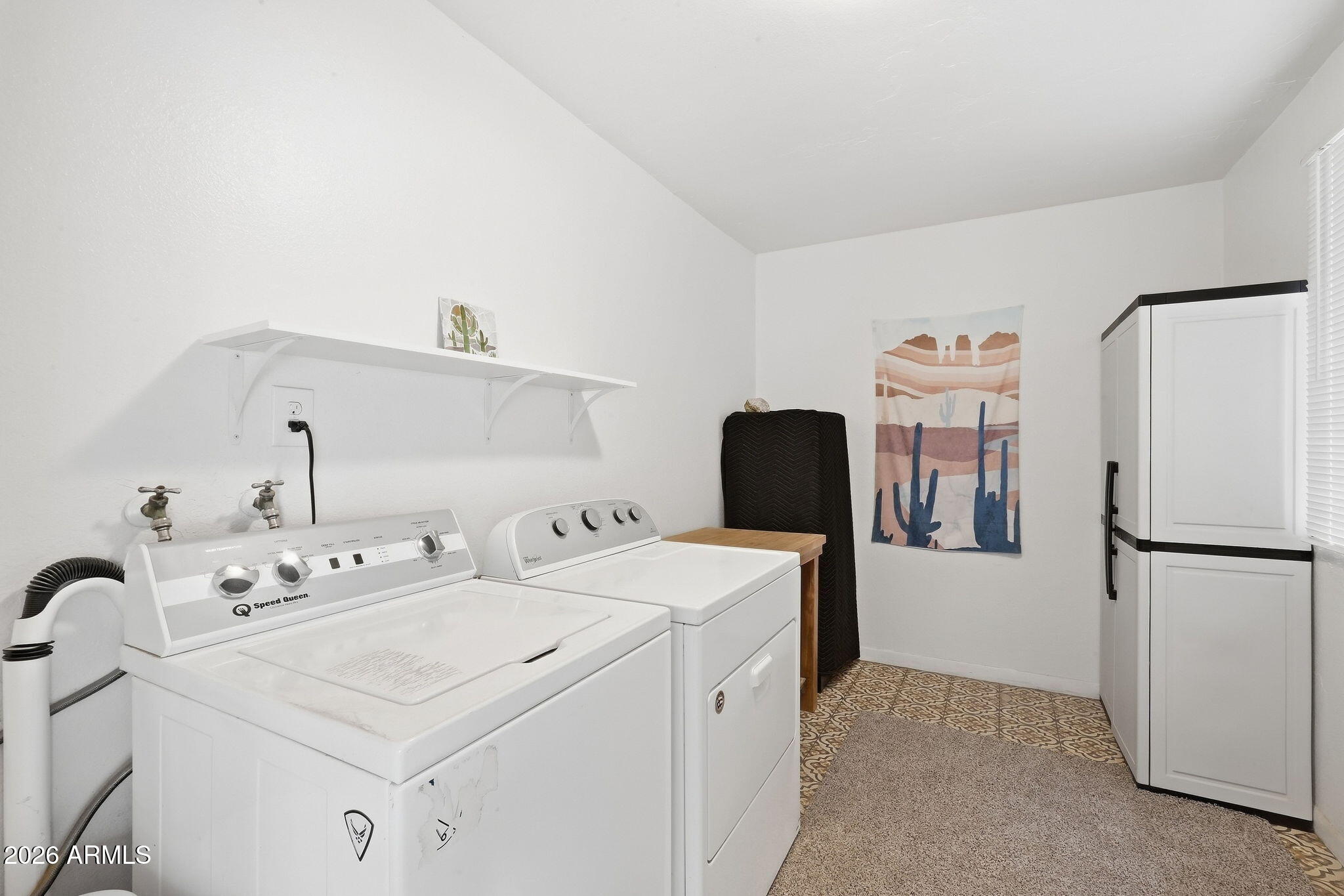 Laundry room with white washer and dryer, tall storage cabinet, and patterned tile floor.