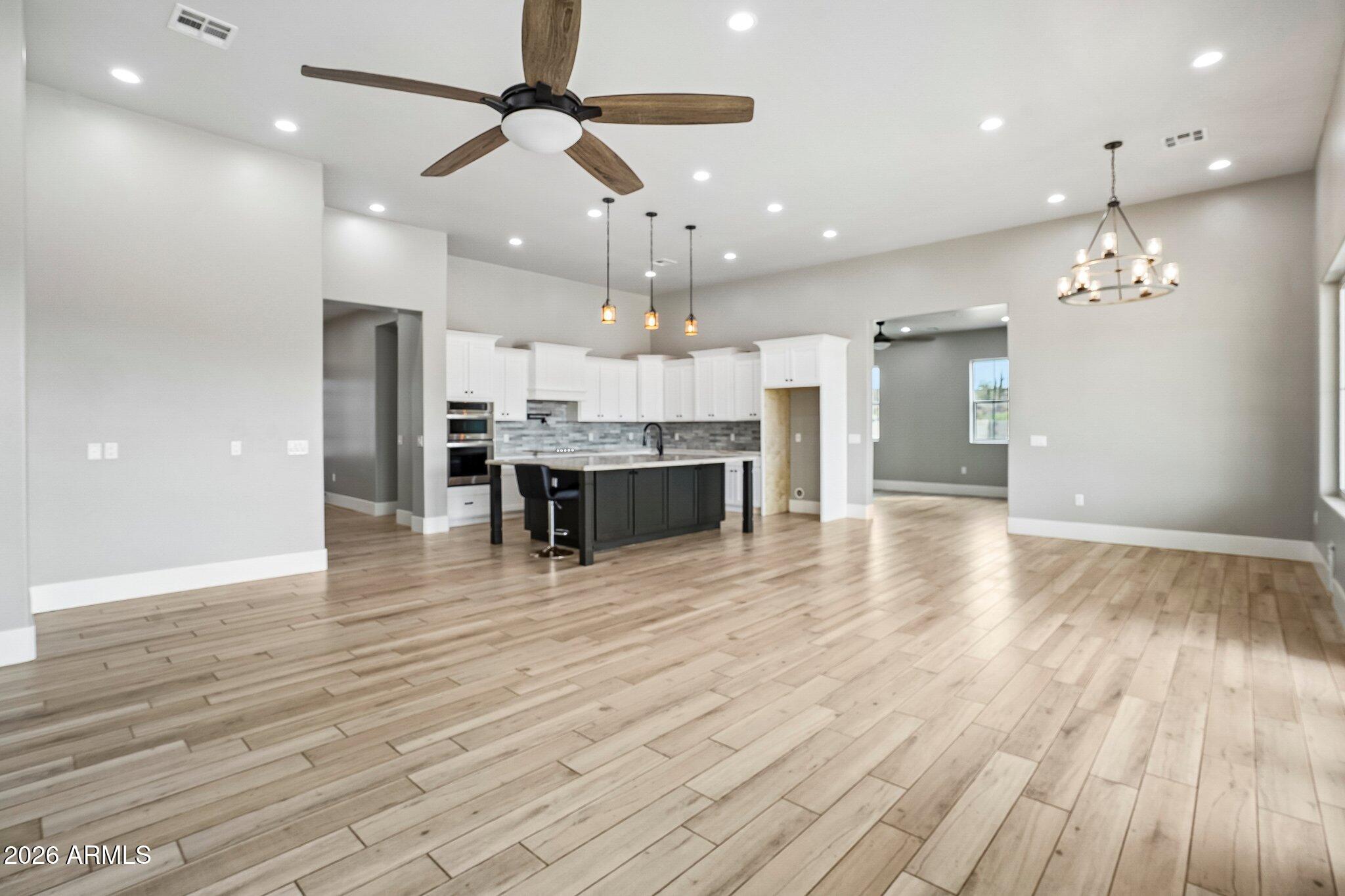 Open kitchen and living area with a dark island, white cabinets, and wood-look tile flooring.