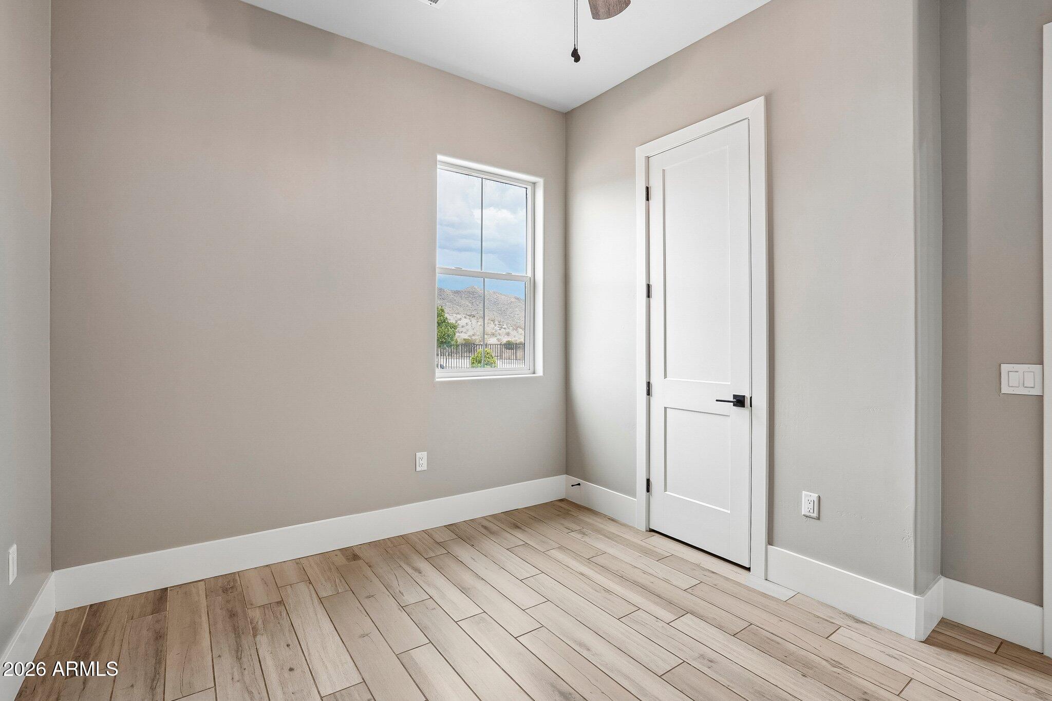 Empty room with plank flooring and a window framing a mountain view.