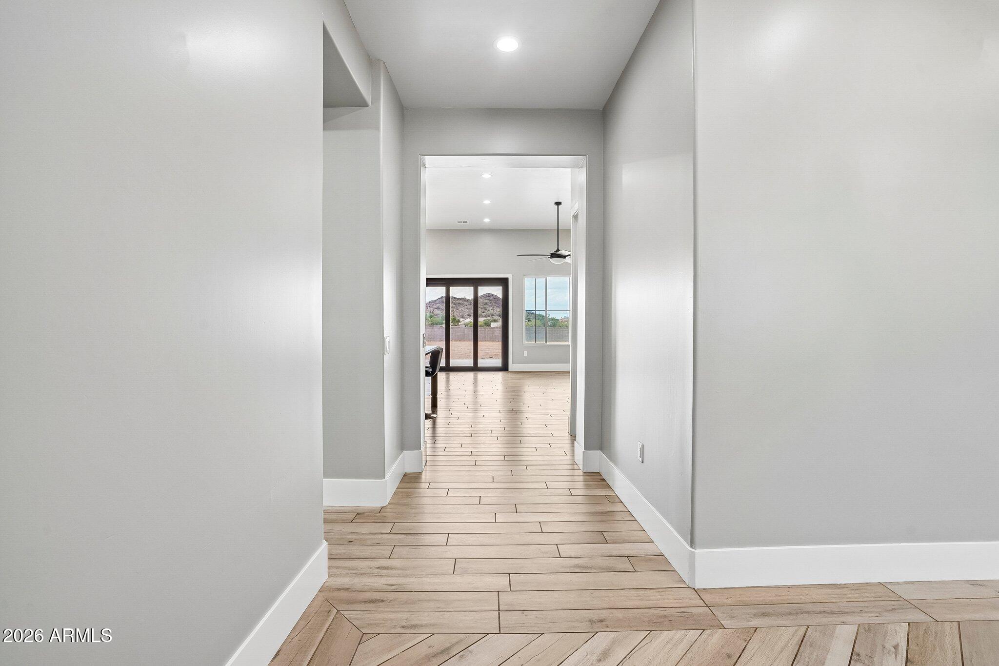 Hallway with wood-look tile flooring opening to a room with glass doors and a mountain view.