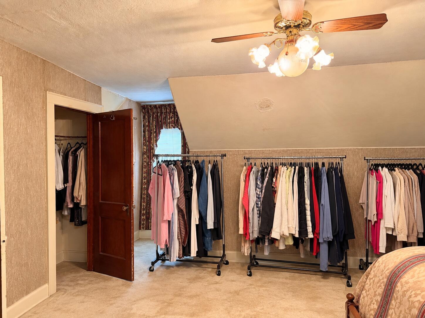 Walk-in closet with clothing racks, an open closet, and a wooden ceiling fan.