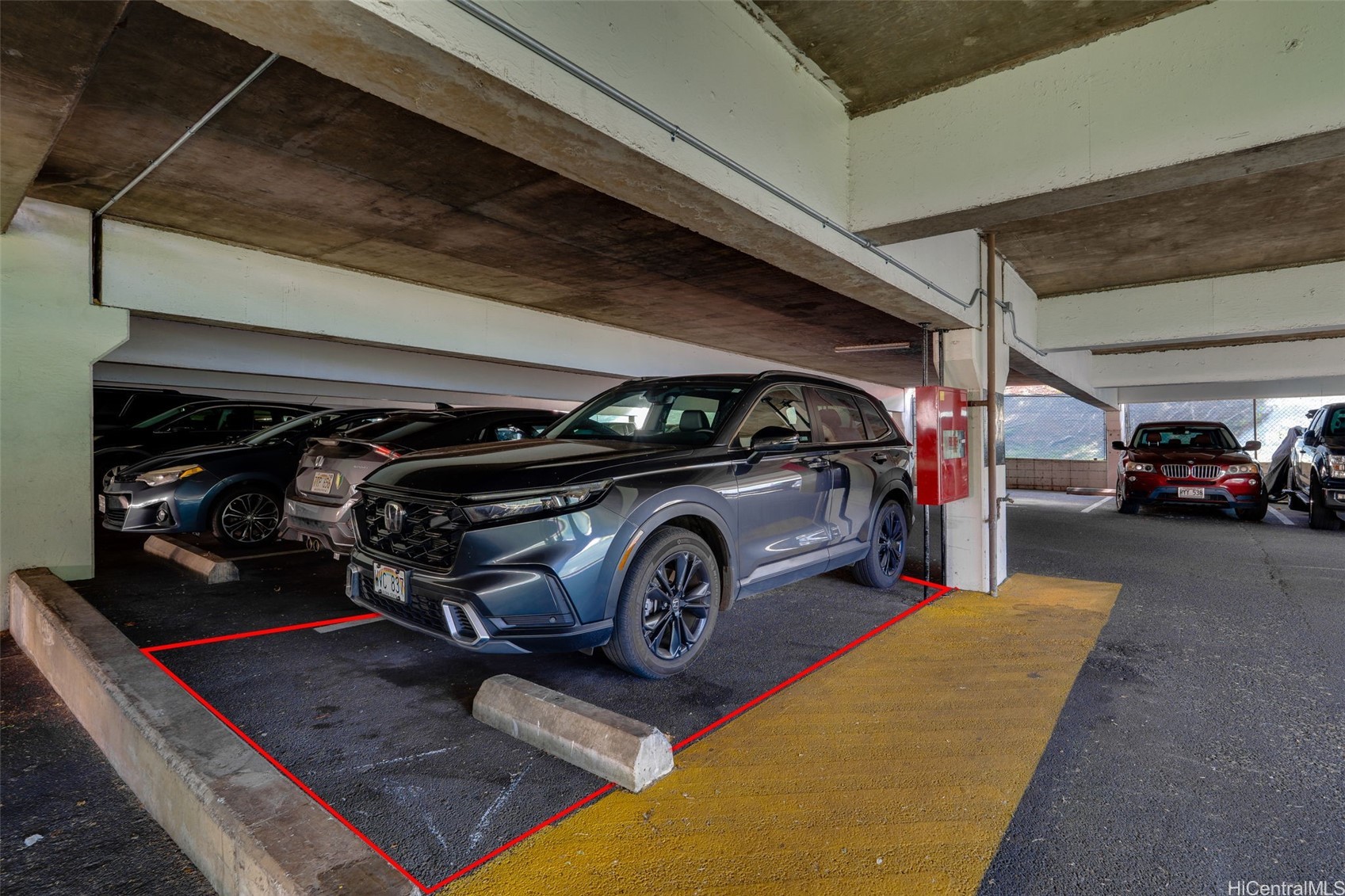 Covered parking stall outlined in red, with a blue SUV parked inside.