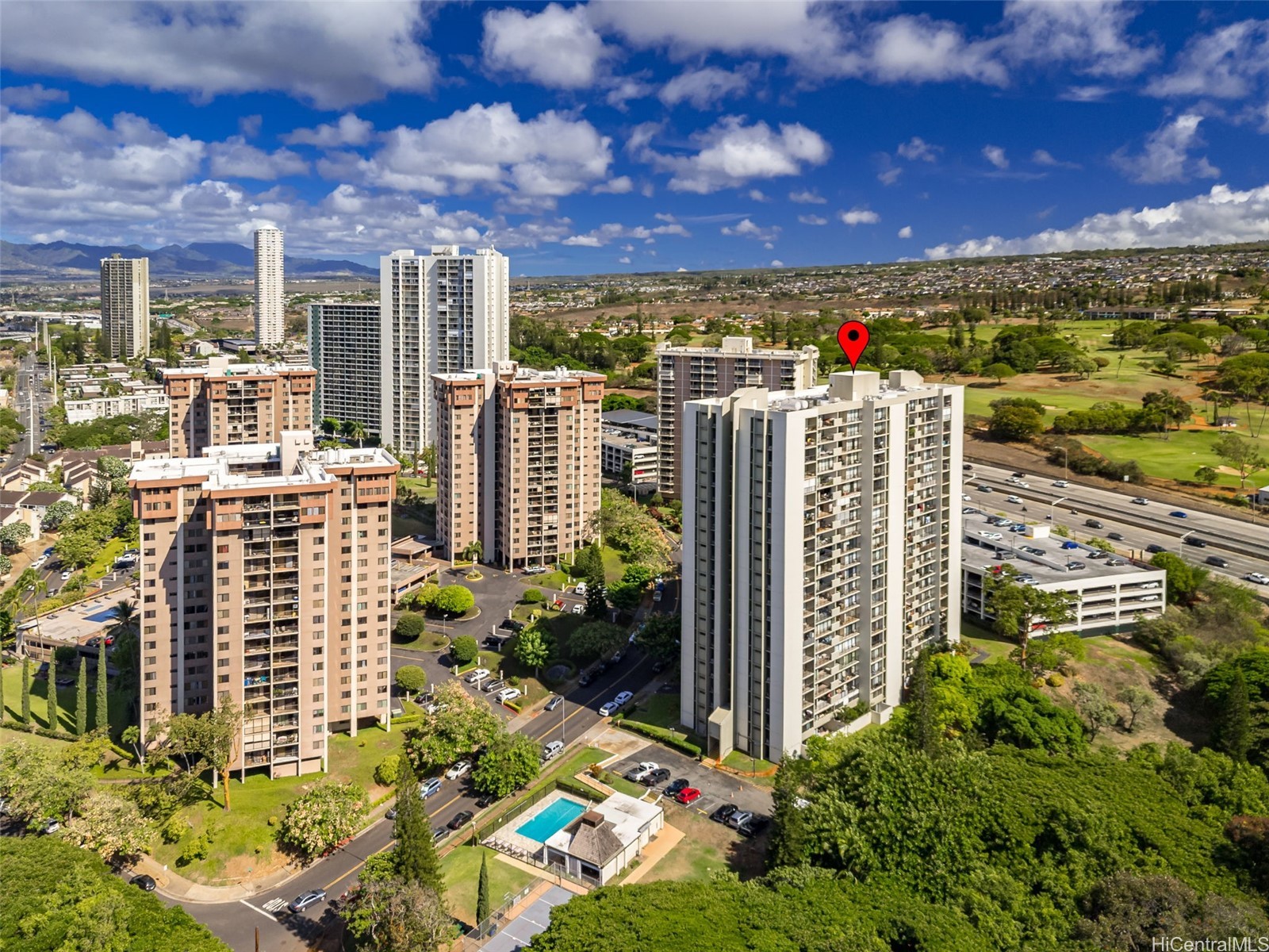 Aerial view of Koauka Loop condominium towers, with a red pin marking one building beside a golf course.