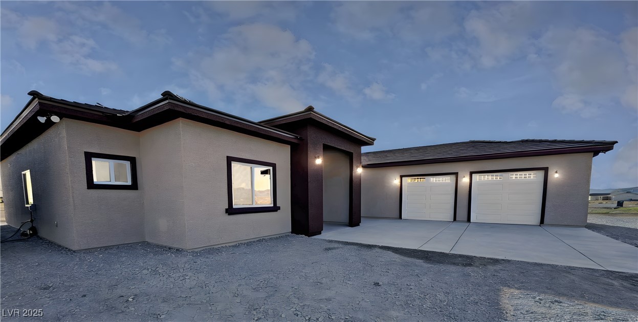 Single-story stucco home with dark trim, a covered entry, and an attached two-car garage.