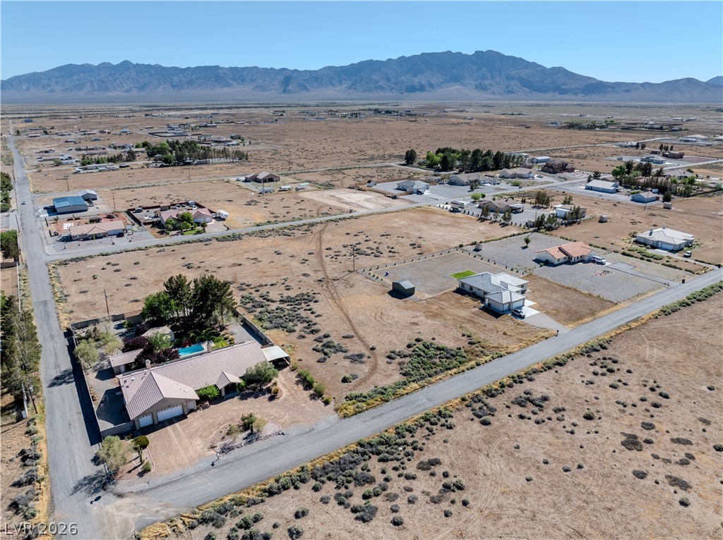 Aerial view of open desert lots and scattered homes, with mountains in the distance.
