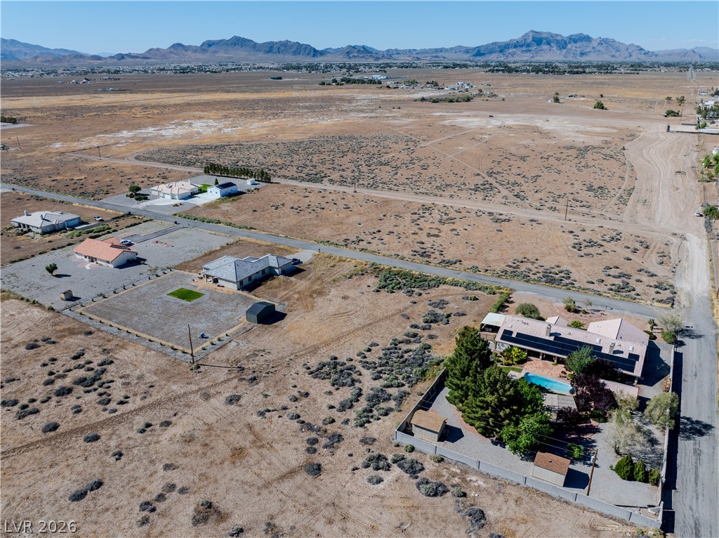 Aerial view of desert homes and open scrubland with mountains in the distance.