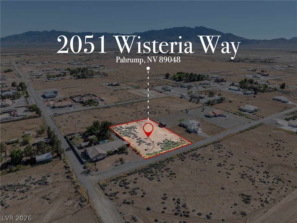 Vacant desert lot outlined in red, surrounded by rural homes with mountains in the distance.