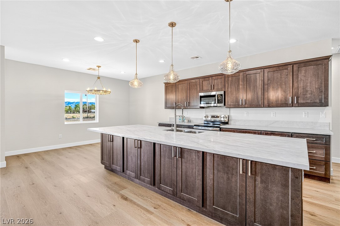 Vacant kitchen with a large white island, dark wood cabinetry, and distant mountains visible through the window.