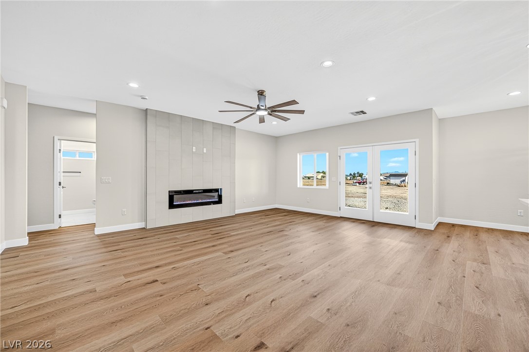 Vacant living room with a tiled linear fireplace, light wood floors, and glass doors to the yard.