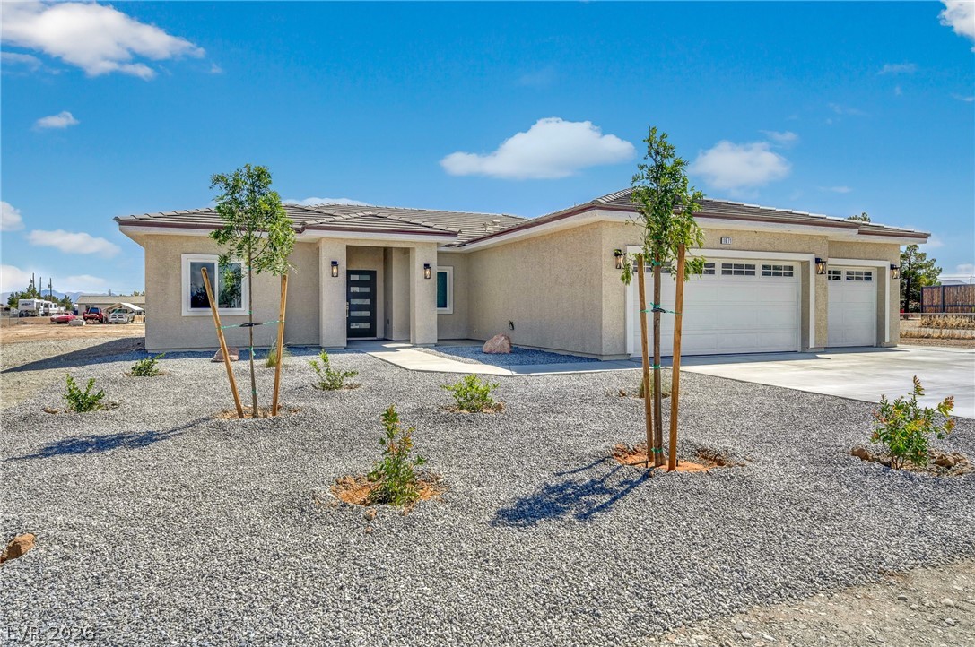 Single-story stucco home with two garage doors and a gravel front yard.