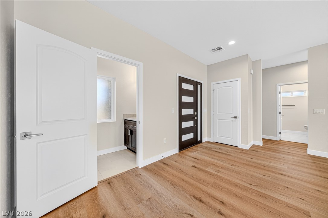 Vacant entryway with warm wood-look floors and a dark front door with horizontal glass panels.