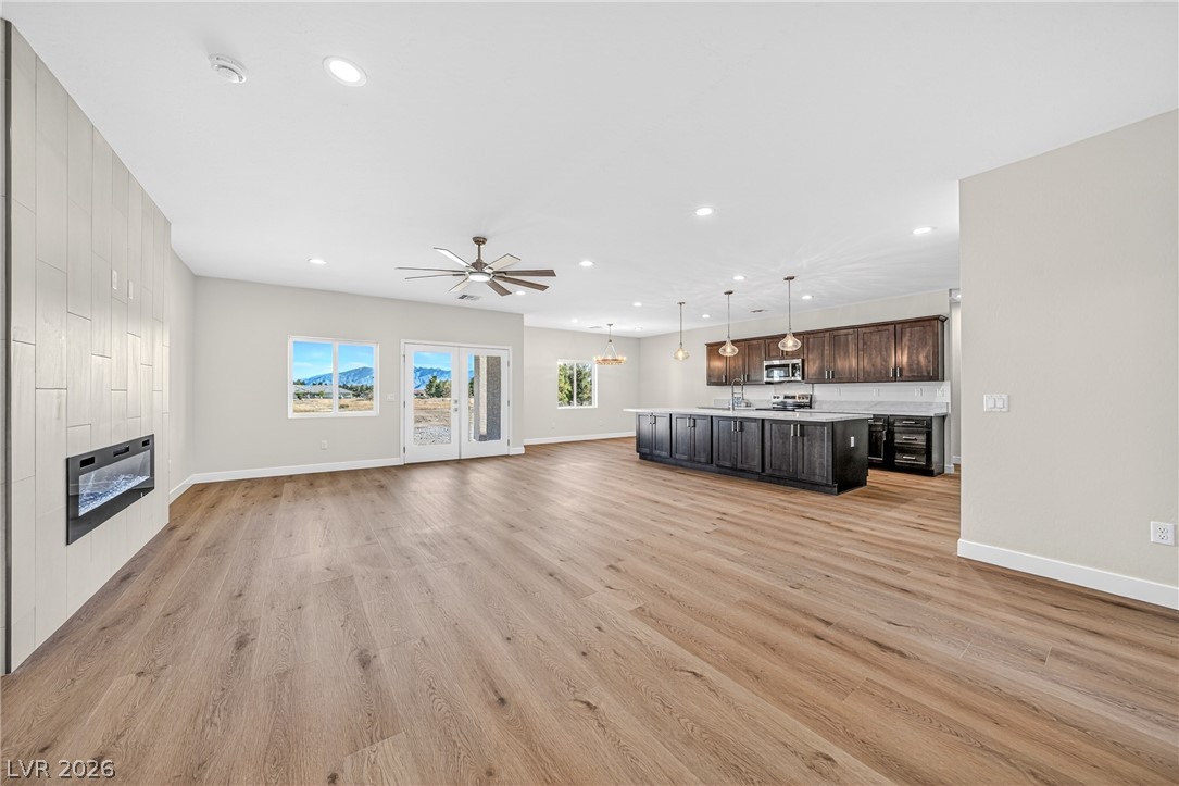 Open-plan kitchen with dark cabinetry, a large island, wood floors, and mountains visible through the windows.