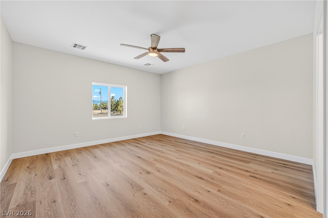 Empty room with wood-look flooring, a ceiling fan, and a window overlooking mountains.