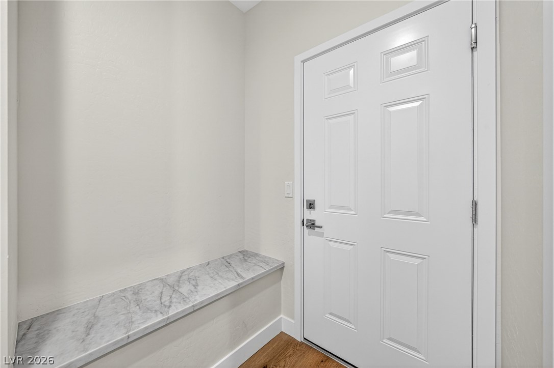 Entryway with a white paneled front door, marble-look ledge, and wood flooring.
