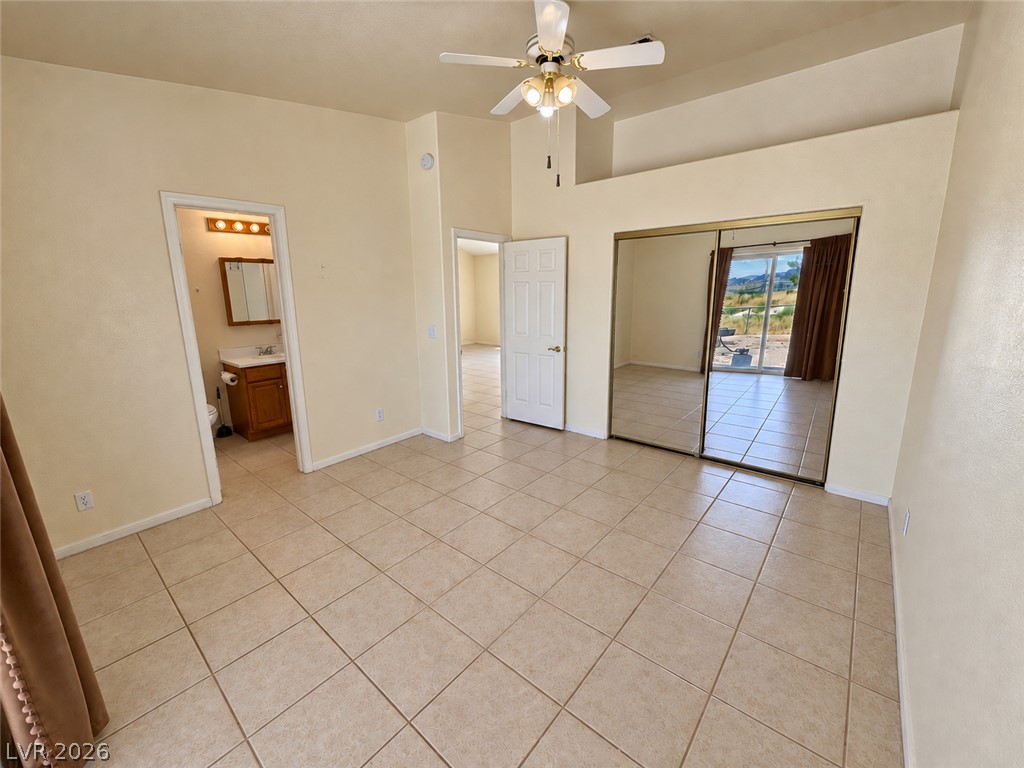 Vacant bedroom with mirrored closet doors, tiled floors, and sliding doors to a patio.