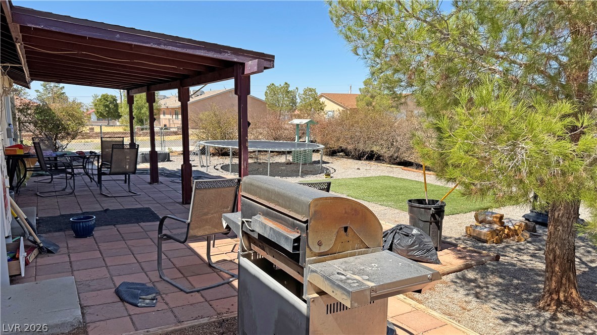 Backyard patio with a covered seating area, large grill, above-ground pool, and artificial turf.