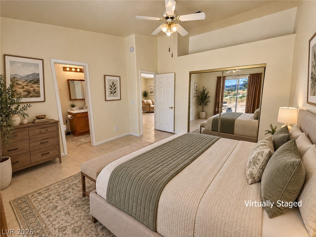 Virtually staged bedroom with a large upholstered bed, mirrored closet doors, and an ensuite bathroom.