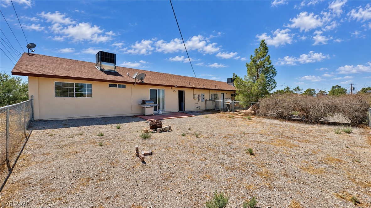 Rear of a single-story stucco property with a gravel yard and chain-link fencing.