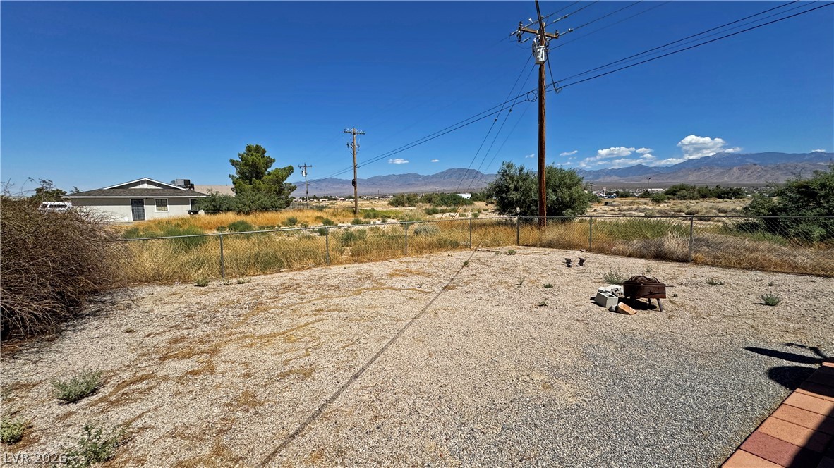 Gravel backyard with chain-link fencing, a fire pit, and distant mountain views.