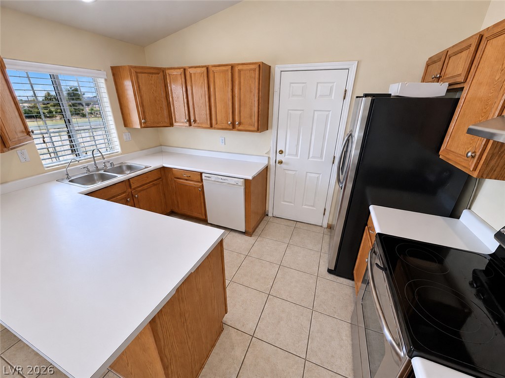 Kitchen with wood cabinets, white countertops, a large peninsula, and black appliances.