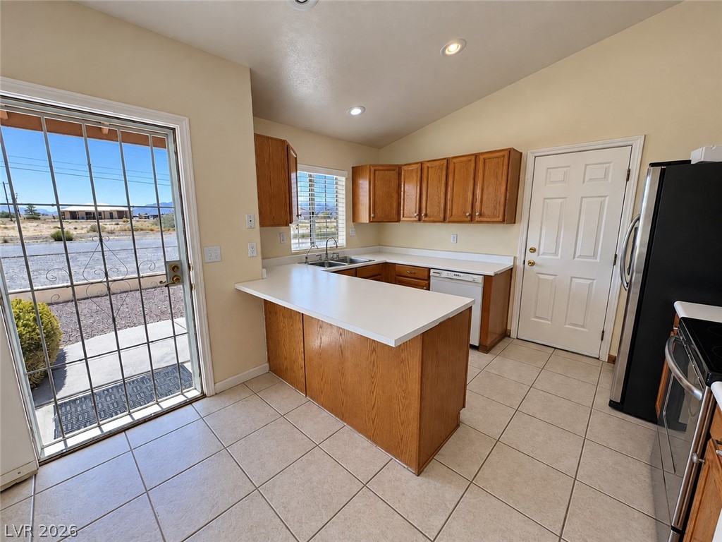 Kitchen with wood cabinets and a white peninsula beside a barred sliding glass door.