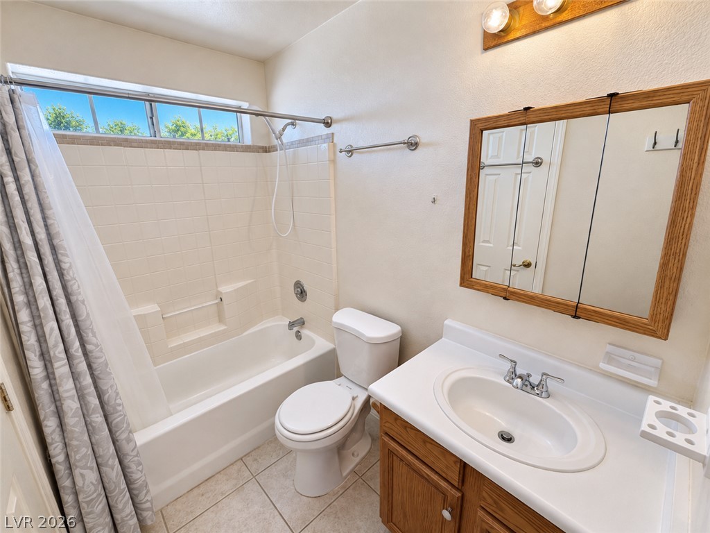 Bathroom with a tiled tub and shower, wood vanity, and high horizontal window.