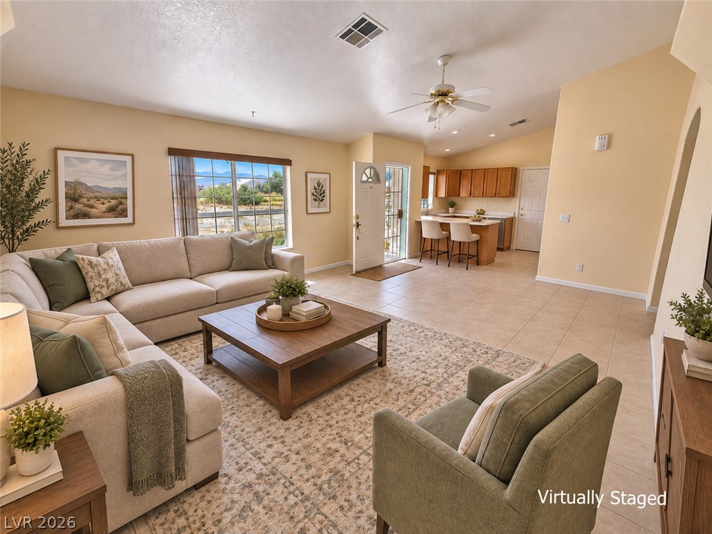 Virtually staged living room with a sectional, armchairs, patterned rug, and open kitchen.