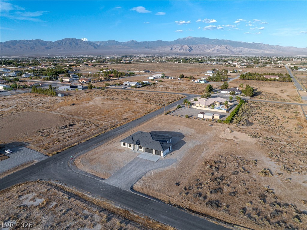 Aerial view of a newly built home on a large desert lot with mountains beyond.