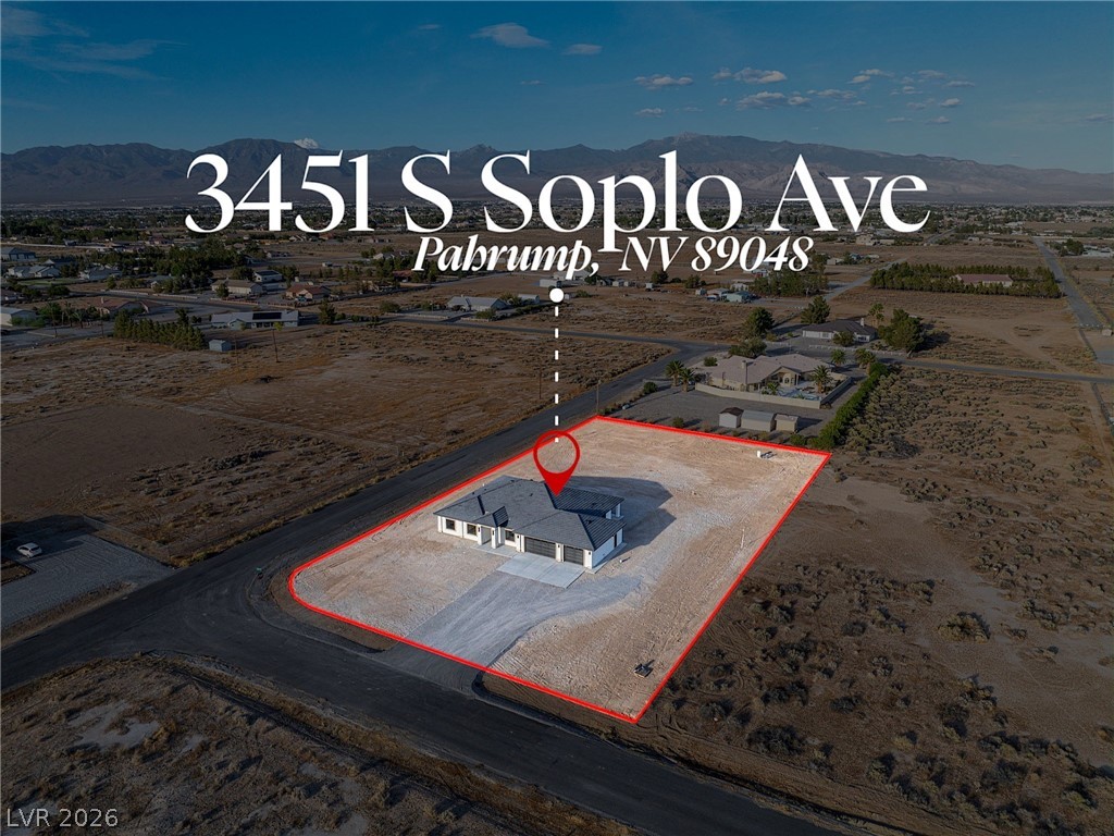 Aerial view of a single-story home on a large outlined lot, with mountains in the distance.