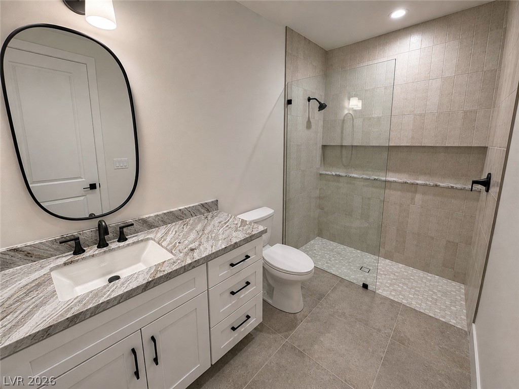 Bathroom with a veined stone vanity countertop and glass-enclosed tiled walk-in shower.