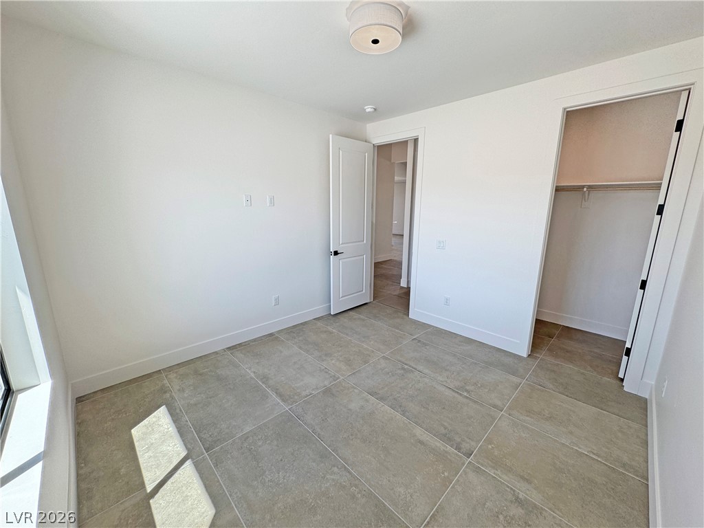 Empty room with large tile flooring, a window, and an open closet.
