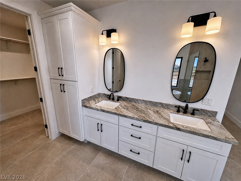Bathroom with a double-sink vanity, veined stone countertop, black faucets, and oval mirrors.