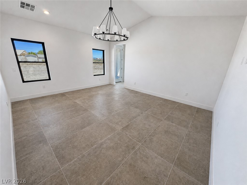 Vacant tiled room with a black circular chandelier and two windows.