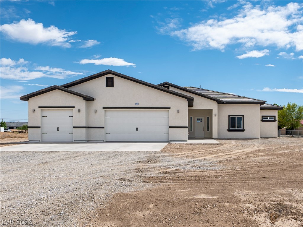 Single-story home with two garage doors and a broad gravel yard.