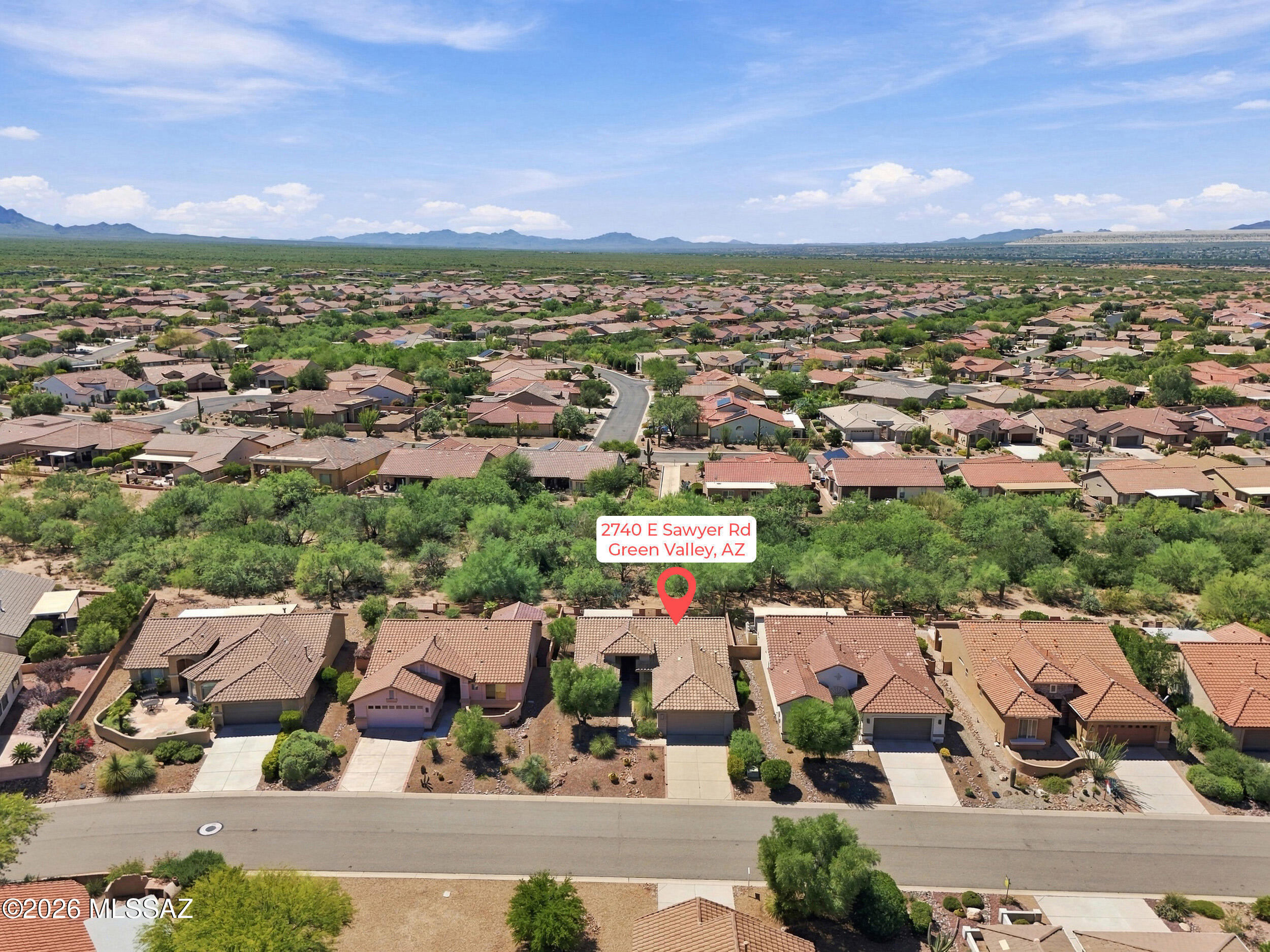 Aerial view of a Green Valley home marked by a red pin, with desert landscaping and mountains beyond.